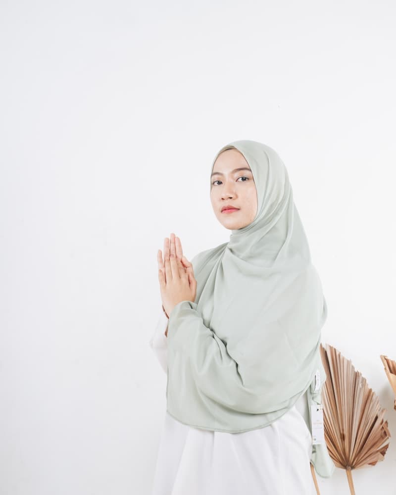 Hijab sage green difoto dengan latar belakang studio putih bersih