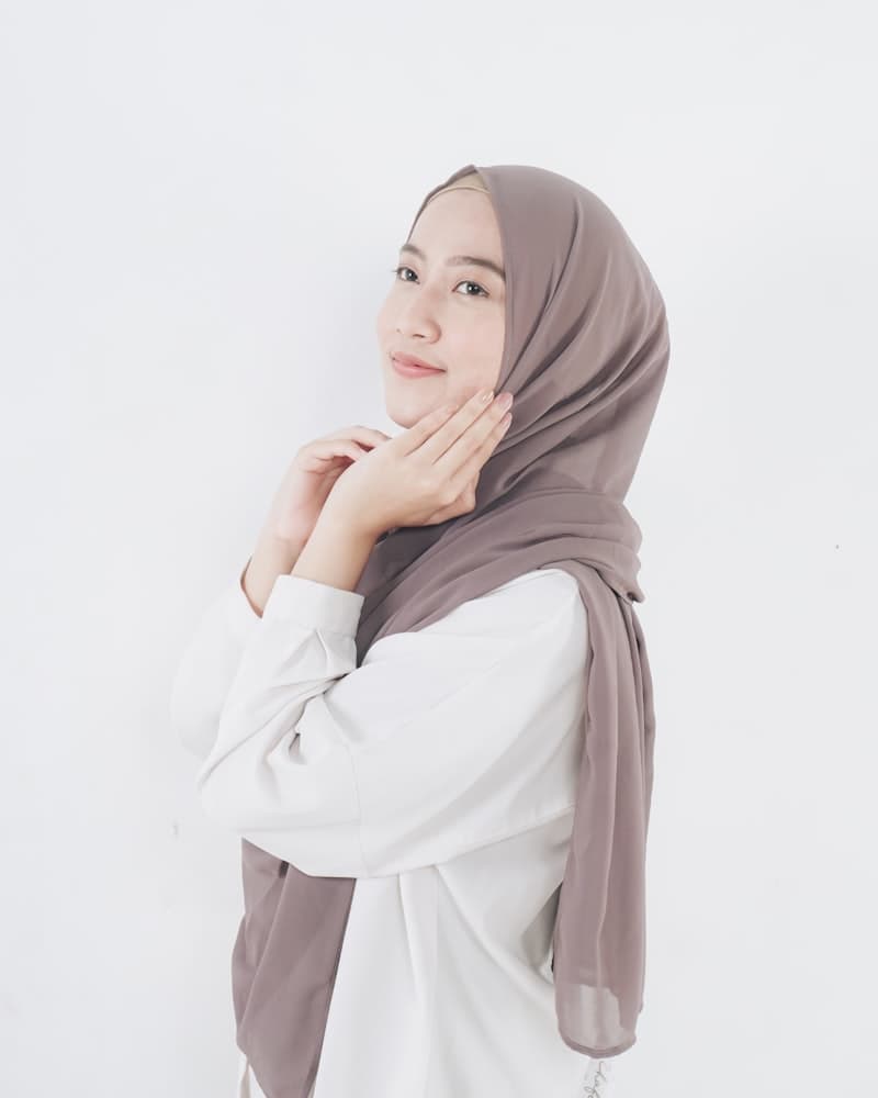 Clean studio portrait of woman in hijab showing the neutral background style required for passport photos